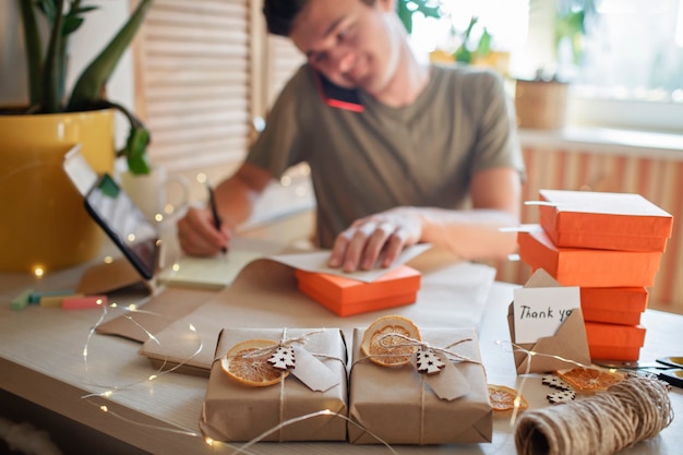 Zdjęcie młody pracownik pakujący świąteczne pudełka na prezenty dla klientów rodzina mała firma daleka praca z domu