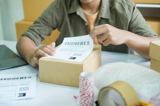 Młody przedsiębiorca pakujący produkt zamów online do wysyłki