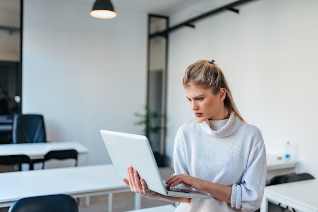 Młody przypadkowy bizneswoman używa laptop indoors.