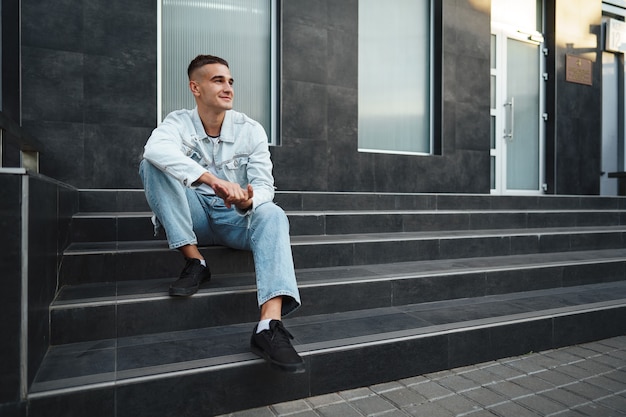 Młody przypadkowy mężczyzna siedzący samotnie na schodach na ulicy