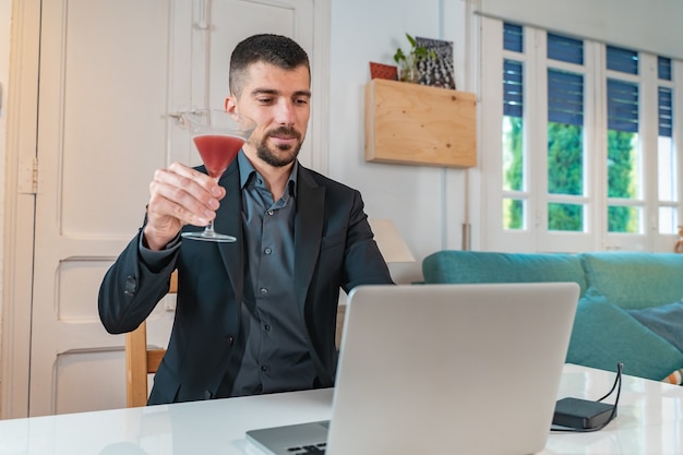 Młody przystojny biznesmen przy drinku podczas rozmowy wideo online
