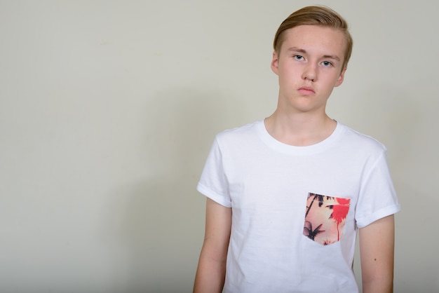Zdjęcie młody przystojny blond nastoletni chłopak przeciw białej przestrzeni