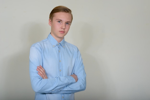 młody przystojny blond nastoletni chłopak z inteligentną odzież na co dzień przeciw białej przestrzeni