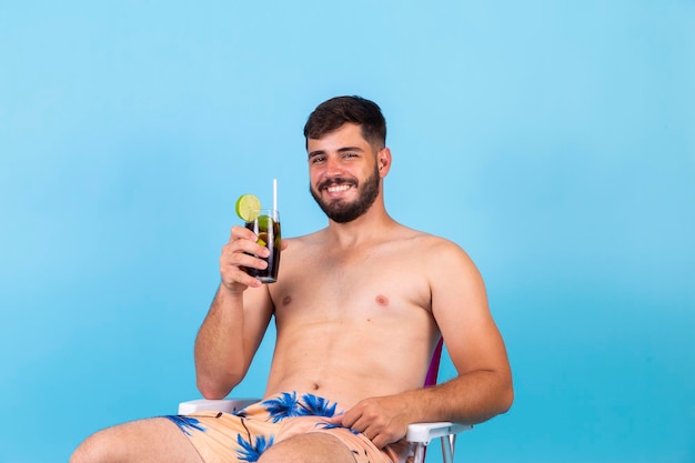 Młody przystojny chłopak korzystających z wakacji picie zimnej coli sody Mężczyzna jest na wakacjach siedząc na krześle plaży popijając drinka