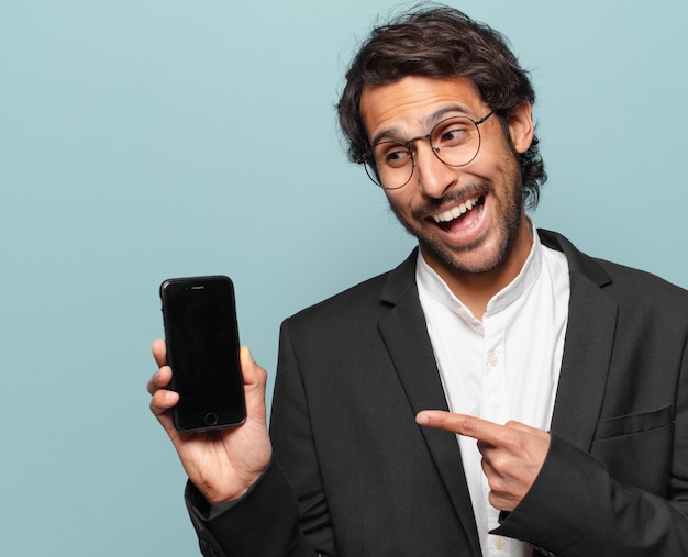 Młody przystojny indyjski biznesmen pokazuje swój telefon pusty ekran