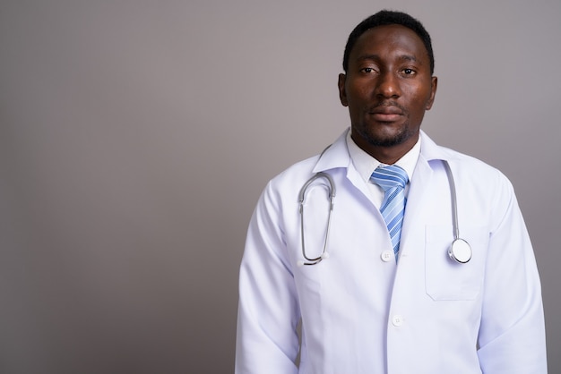 Młody przystojny mężczyzna Afryki lekarz na szarym tle