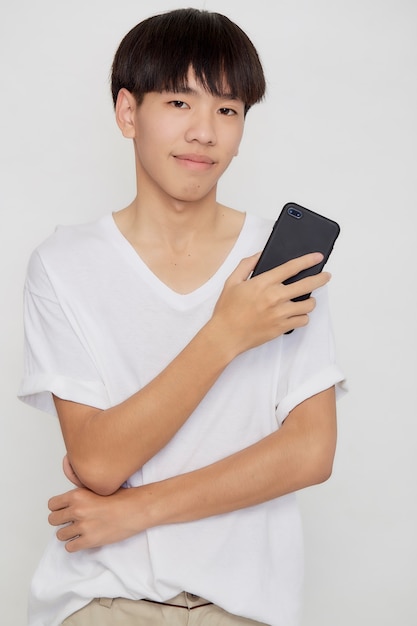 Młody przystojny mężczyzna azjatyckich posiadania telefonu komórkowego na tle białego studia