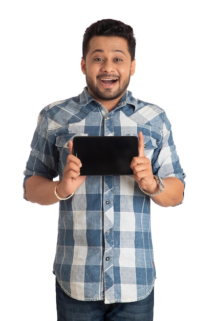 Młody przystojny mężczyzna biznesmen pokazuje pusty ekran smartfona lub telefonu komórkowego lub tabletu na białym tle
