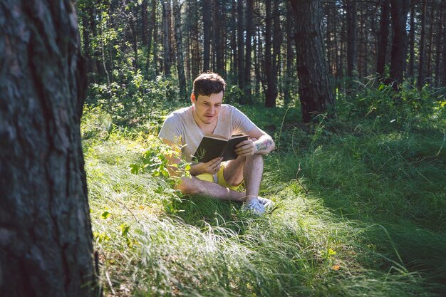 Młody przystojny mężczyzna czyta książkę w otwartej przestrzeni