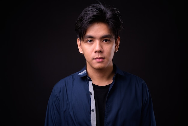 młody przystojny mężczyzna Filipino na czarnej ścianie
