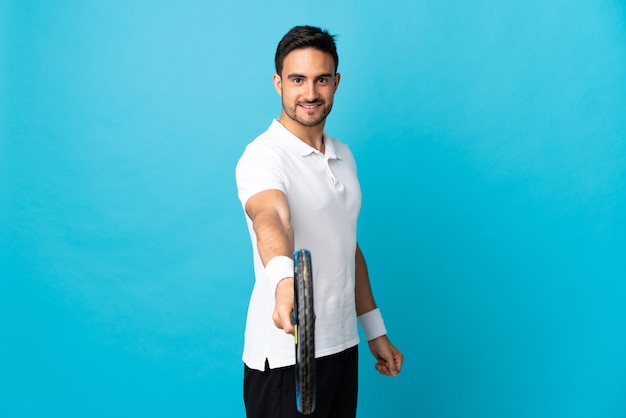 Zdjęcie młody przystojny mężczyzna na białym tle na niebieskim tle, grać w tenisa