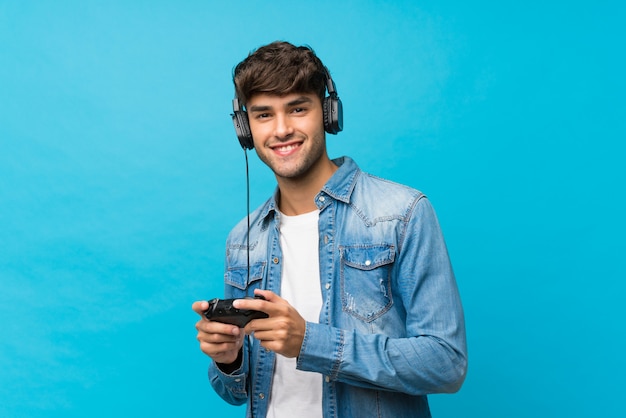 Młody przystojny mężczyzna nad odosobnionym błękitem bawić się przy gra wideo