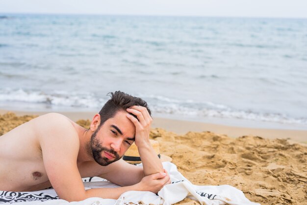 Młody przystojny mężczyzna relaksuje na plaży