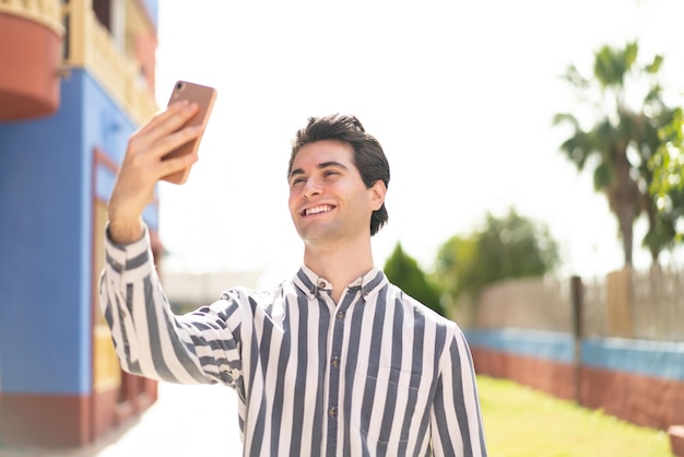 Młody przystojny mężczyzna robi selfie z telefonem komórkowym