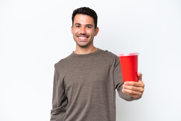 Młody przystojny mężczyzna trzyma napój gazowany na białym tle ze szczęśliwym wyrazem twarzy