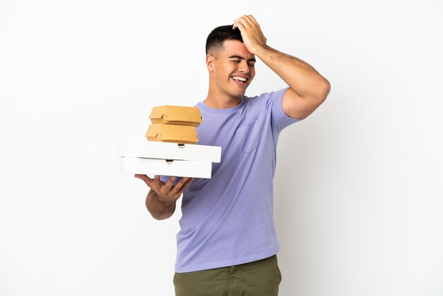 Młody przystojny mężczyzna trzymający pizze i hamburgery na białym tle uświadomił sobie coś i zamierza znaleźć rozwiązanie