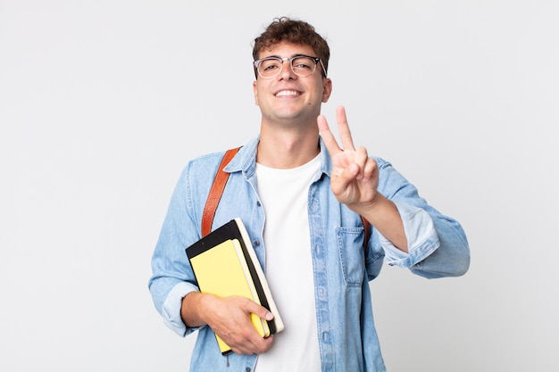 Młody Przystojny Mężczyzna Uśmiecha Się I Wygląda Na Szczęśliwego, Wskazując Na Zwycięstwo Lub Pokój. Koncepcja Studenta Uniwersytetu