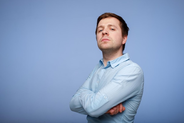 Młody przystojny mężczyzna w niebieskiej koszuli pewnie patrzy w kamerę