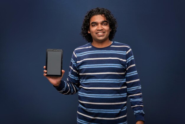 Młody przystojny młody człowiek biznesmen pokazując pusty ekran smartfona lub telefonu komórkowego lub tabletu na szarym tle