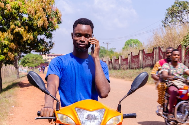 Młody Przystojny Motocyklista Z Afryki Dzwoni W Oczekiwaniu Na Przybycie Klienta