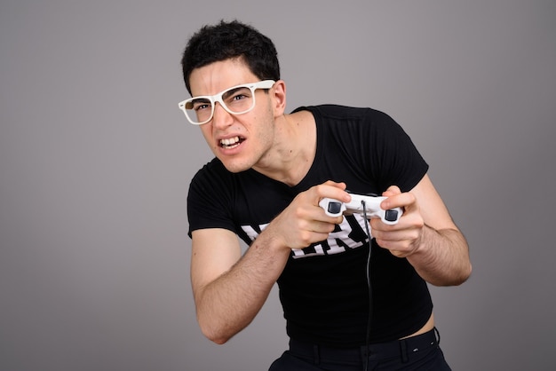 Zdjęcie młody przystojny nerd mężczyzna z okularami przeciw szarości