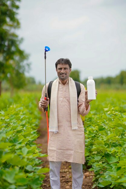 Młody rolnik indyjski pokazano butelkę płynnego nawozu w dziedzinie rolnictwa.