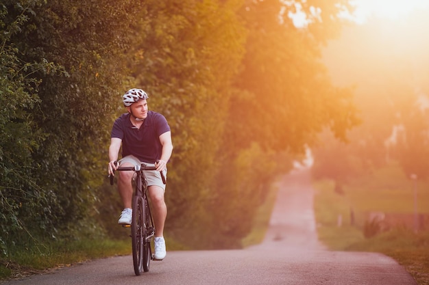 Młody rowerzysta płci męskiej prowadzący aktywny tryb życia Zdjęcie z przodu przedstawiające rowerzystę jadącego na szutrowym rowerze po wsi
