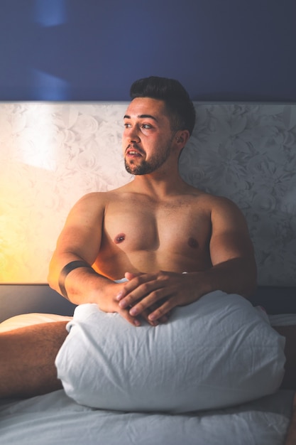 Młody seksowny kaukaski mężczyzna nago na łóżku.