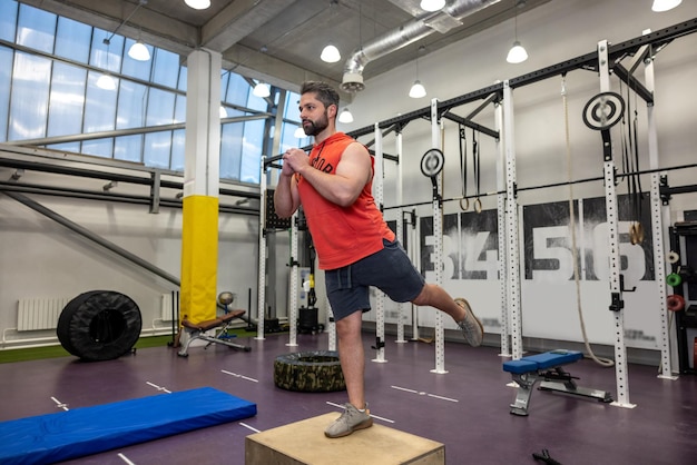 Zdjęcie młody, silny, muskularny mężczyzna ćwiczy z drewnianym pudełkiem w siłowni crossfit