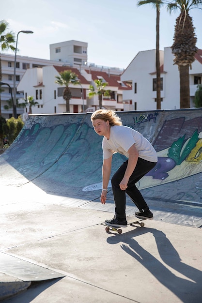 Młody skater bawi się latem w skateparku na rampach