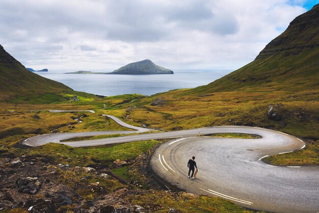 Młody skater ze swoją deskorolką spogląda na piękną scenerię Wysp Owczych