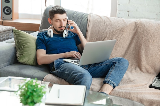 Młody skupiony mężczyzna uczący się w domu podczas kursów online lub samodzielnych bezpłatnych informacji