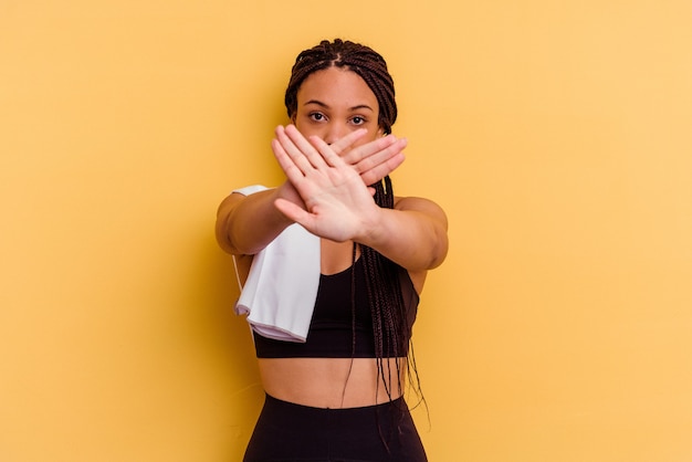 Młody sport African American kobieta trzyma ręcznik na żółtym tle robi gest odmowy
