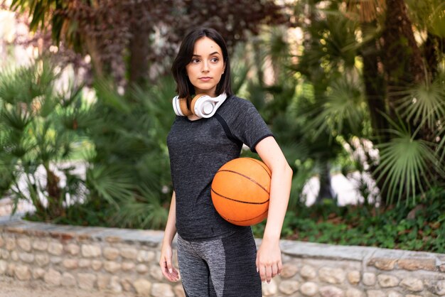 Młody sport kaukaski kobieta trzyma piłkę do koszykówki na zewnątrz w parku
