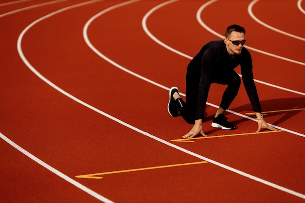 Młody sportowiec biega po stadionie ubrany w czarną odzież sportową, przygotowując się do zawodów