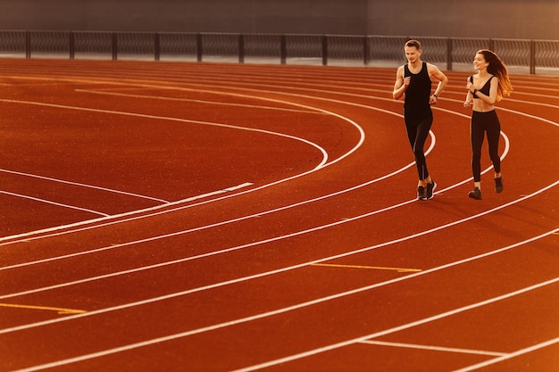 Młody sportowiec biega po stadionie ubrany w czarną odzież sportową, przygotowując się do zawodów