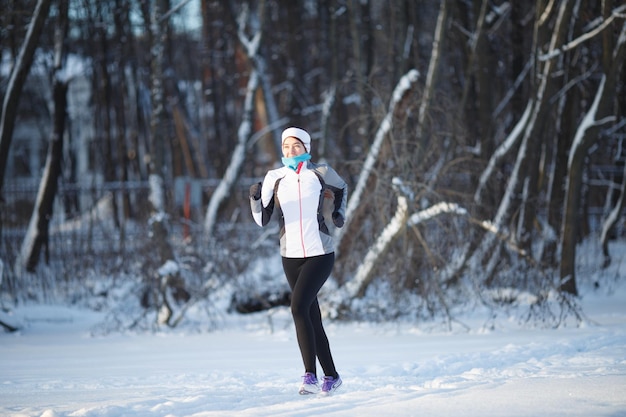 Młody sportowiec biegający w zimowym lesie w sportowej formie