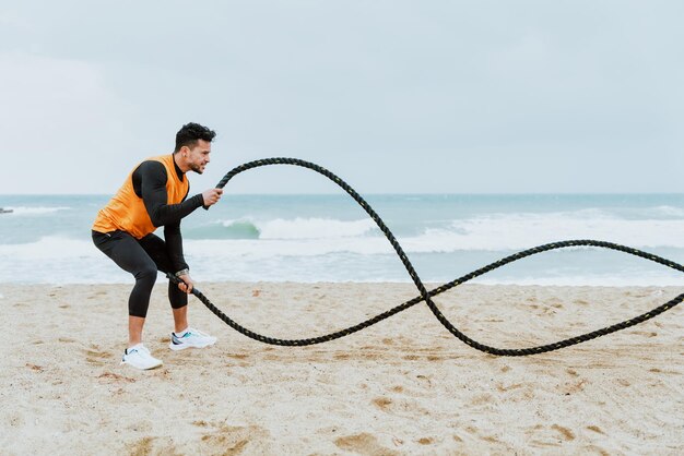 Młody sportowiec trenuje rano na plaży z linami