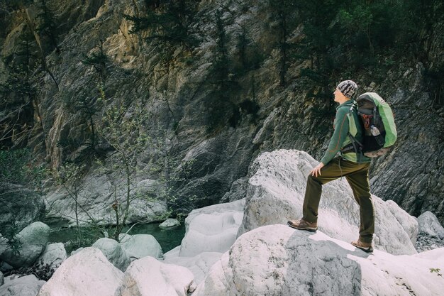 Młody sportowy turysta trekking z plecakiem w górach nad ciemnym lasem z dużymi sosnami. Koncepcja sportu i aktywnego życia.