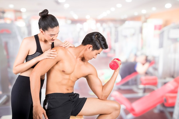 Młody sprawność fizyczna mężczyzna i jego dziewczyna w stażowym gym. Koncepcja fitness i zdrowego stylu życia