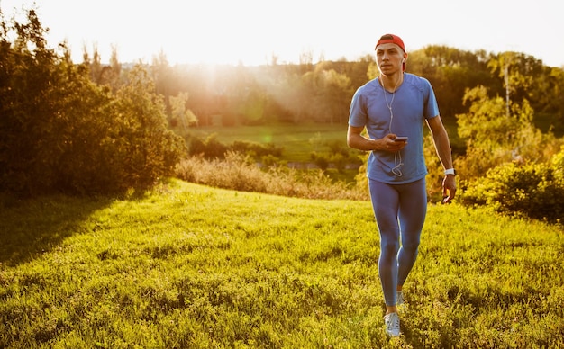 Młody sprawny męski biegacz ćwiczący na zielonej trawie w parku Poziome ujęcie handosme sportowca biegania i sprintu na świeżym powietrzu przygotowania do maratonu Koncepcja sportu i ludzi