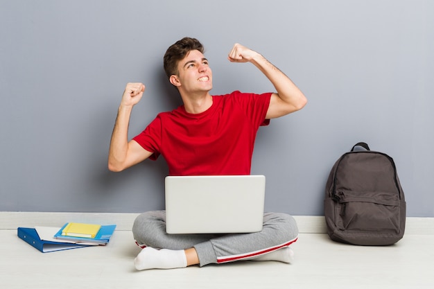 Młody Studencki Mężczyzna Obsiadanie Na Jego Domowej Podłoga Trzyma Laptop