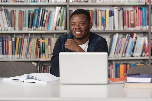 Młody student korzystający z laptopa w bibliotece