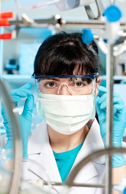Młody Student Medycyny W Masce, Okularów Ochronnych Spojrzenia Na Aparat W Laboratorium Badawczym Badania