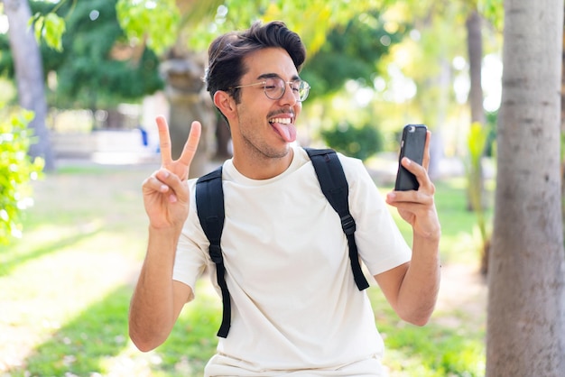 Młody student na zewnątrz przy użyciu telefonu komórkowego