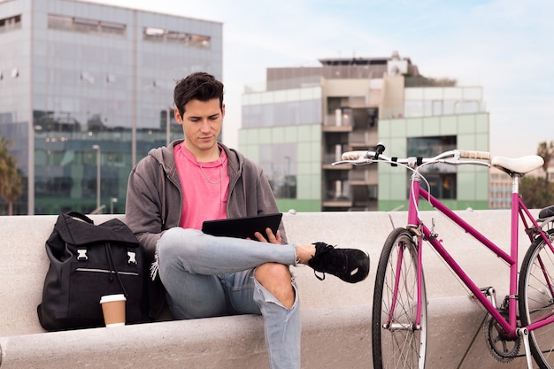 Młody Student Siedzący Na Zewnątrz Za Pomocą Tabletu