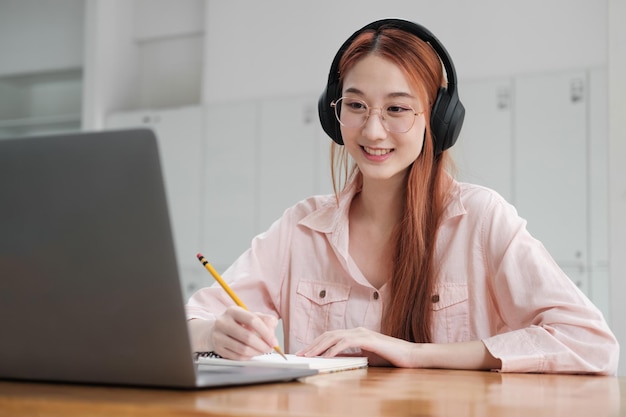 Młody student uczęszczający na studia online za pomocą komputera i urządzenia mobilnego