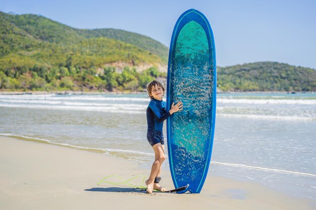 Młody surfer szczęśliwy młody chłopak na plaży z deską surfingową