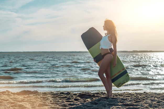 Młody surfingowiec pozuje z jej surfboard na plaży