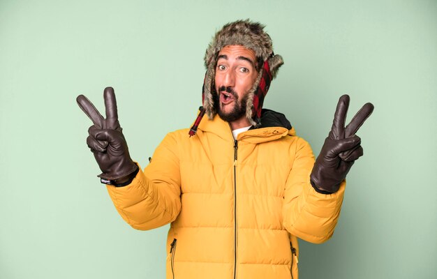 Zdjęcie młody szalony brodaty i ekspresyjny mężczyzna w zimnej i zimowej koncepcji i ubrany w anorak